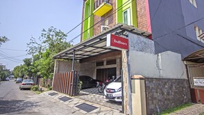 A building with a RedDoorz sign, a covered entrance, and a parked motorcycle. - RedDoorz near Trans Studio Mall 2 (Bandung)
