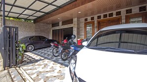 A covered parking area with a car and motorcycles parked. - RedDoorz near Trans Studio Mall 2 (Bandung)