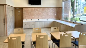 A modern classroom with wooden desks and chairs, a flat-screen TV mounted on the wall, and a window providing a view of the outside. - Toyoko Inn Shonan Kamakura Fujisawa Station Kita (Fujisawa)