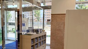 A hotel reception area with a glass door entrance, a reception desk, and a view of the outside. - Toyoko Inn Shonan Kamakura Fujisawa Station Kita (Fujisawa)