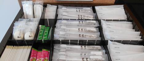 A drawer with various toiletries including toothbrushes, razors, and tea packets.
