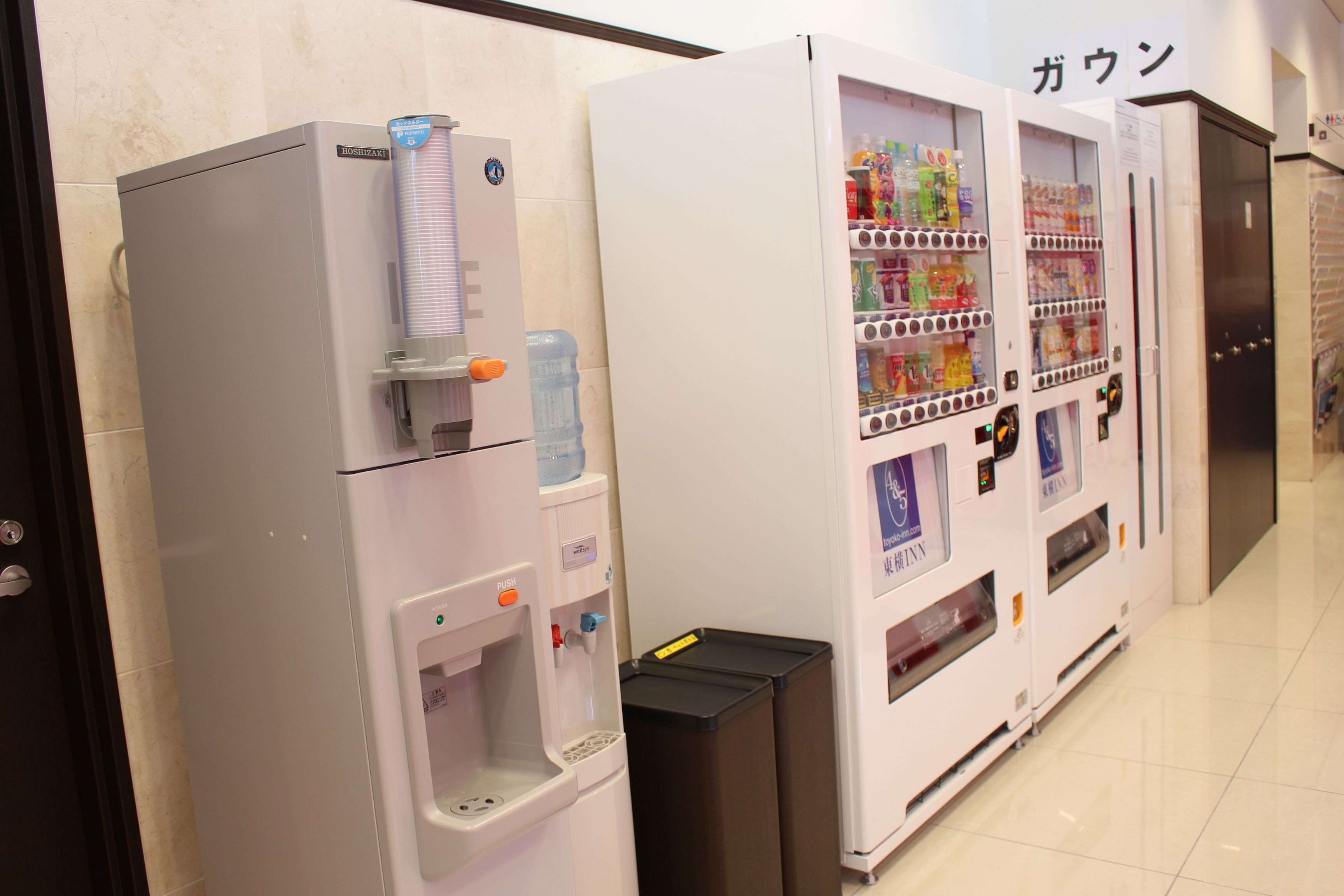 A vending machine with a water dispenser and a beverage vending machine in a hotel corridor.