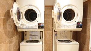 Two front-loading washing machines with control panels, placed in a tiled bathroom. - Toyoko Inn Hanshin Amagasaki Ekimae (Amagasaki)