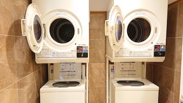 Two front-loading washing machines with control panels, placed in a tiled bathroom.