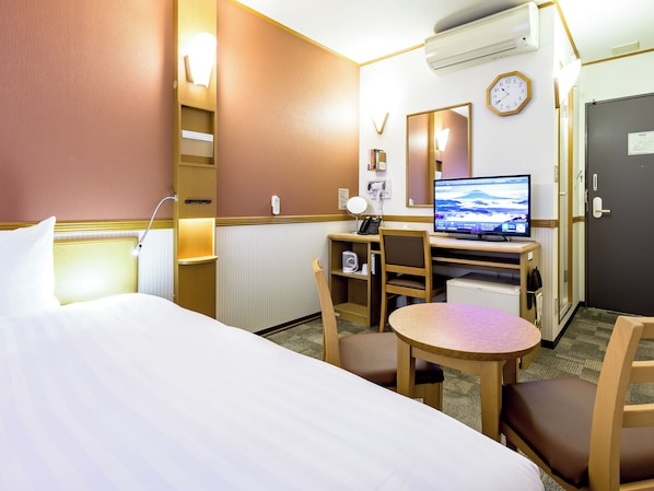 Une chambre d’hôtel avec un lit, un bureau, une chaise, une télévision et une horloge au mur.