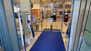 Een moderne hotel lobby met een blauw tapijt, glazen deuren en een receptiebalie.