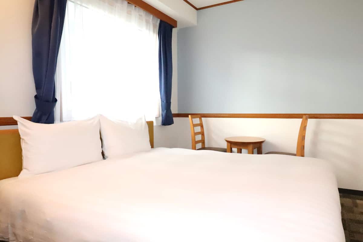 Ein Hotelzimmer mit einem großen Bett, einem kleinen runden Tisch und einem Stuhl.