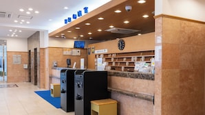 Uma área de recepção de hotel com um relógio digital, um balcão de atendimento e um tapete azul.