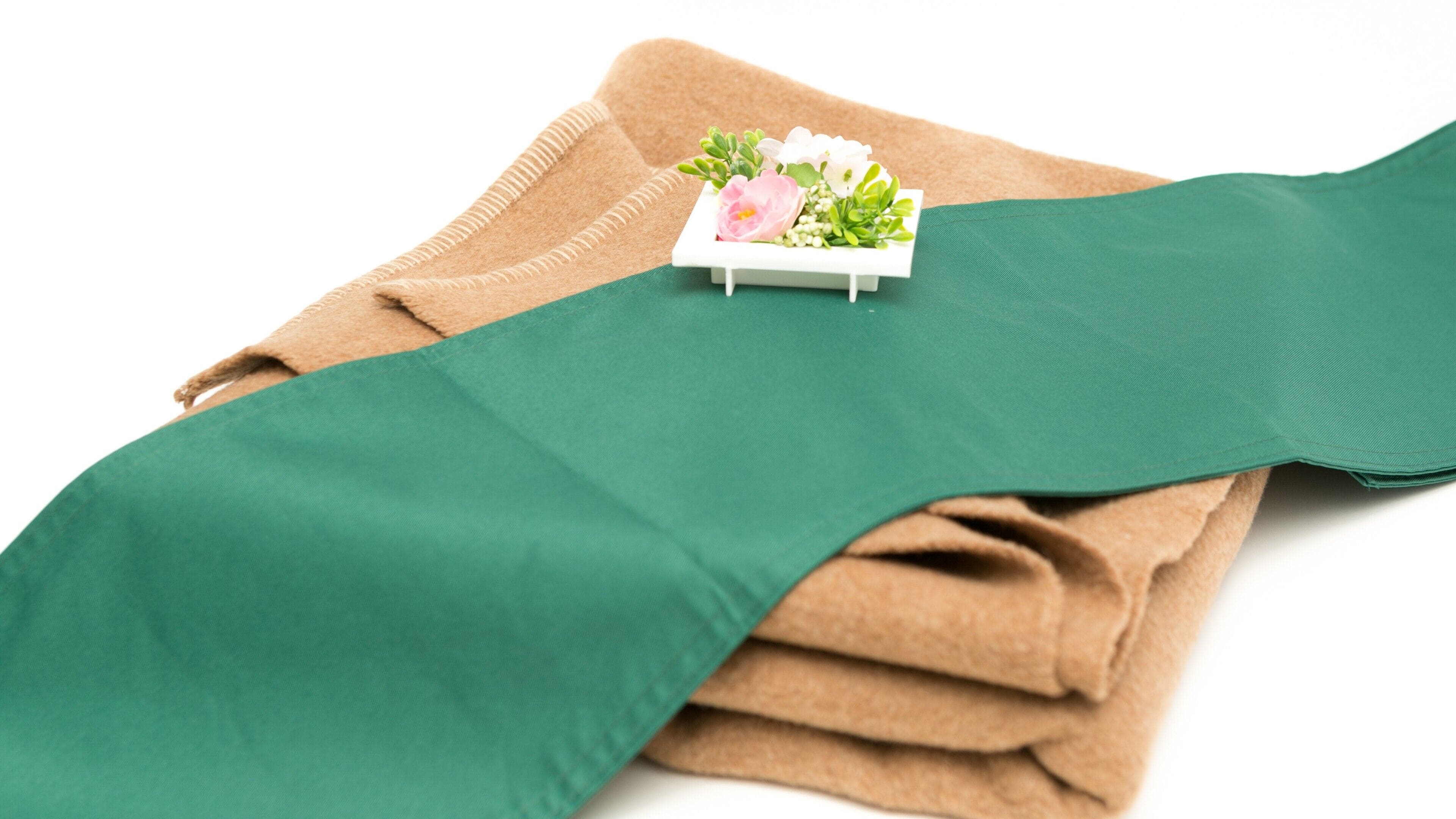 A folded green fabric with a small white box containing flowers on top.