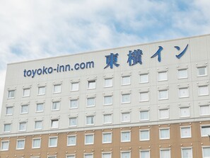 Un edificio de hotel con un letrero que dice "toyoko-inn.com" y "東横イン", indicando que es un Toyoko Inn.