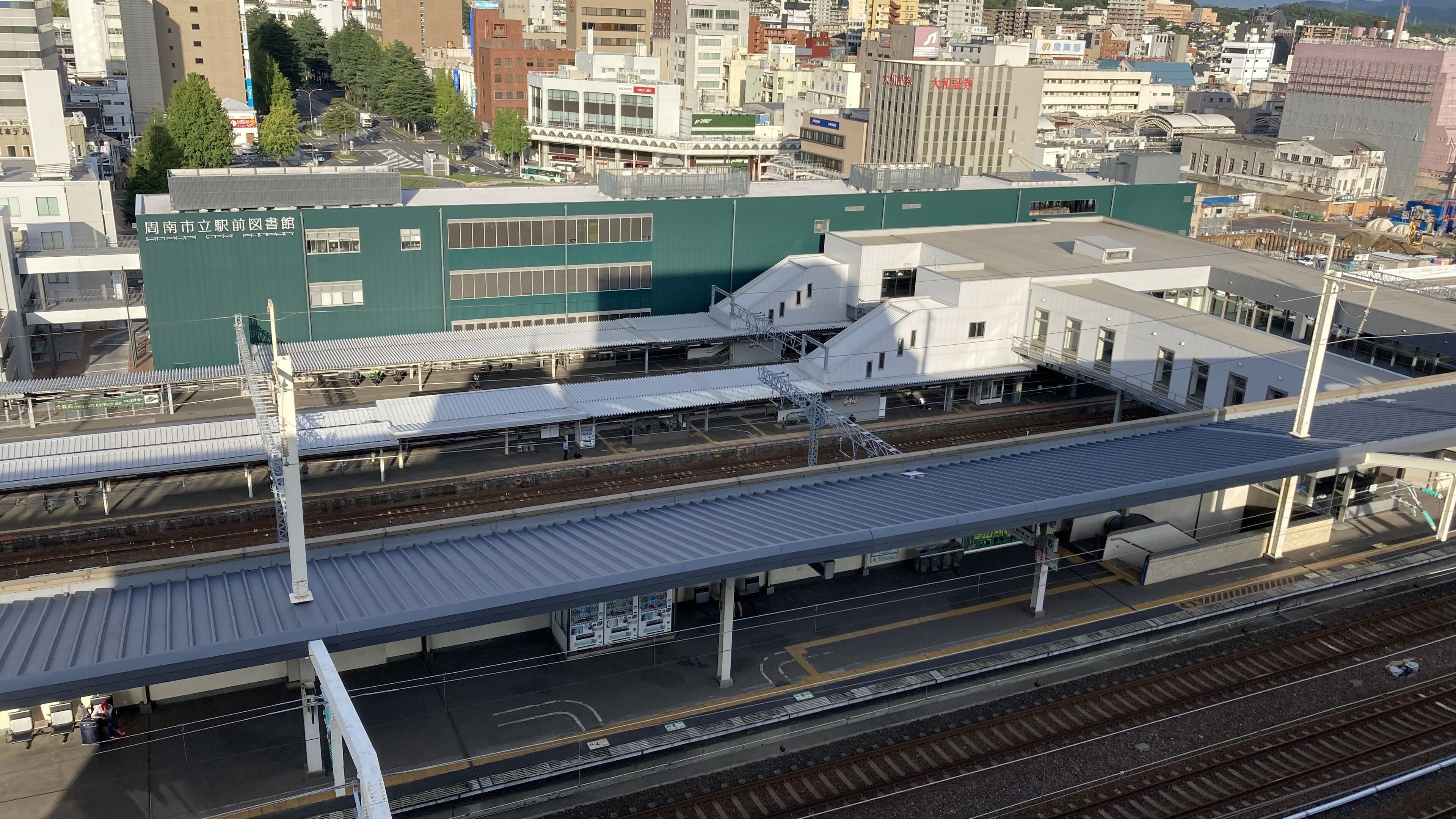 A train station with multiple platforms and tracks, surrounded by urban buildings.