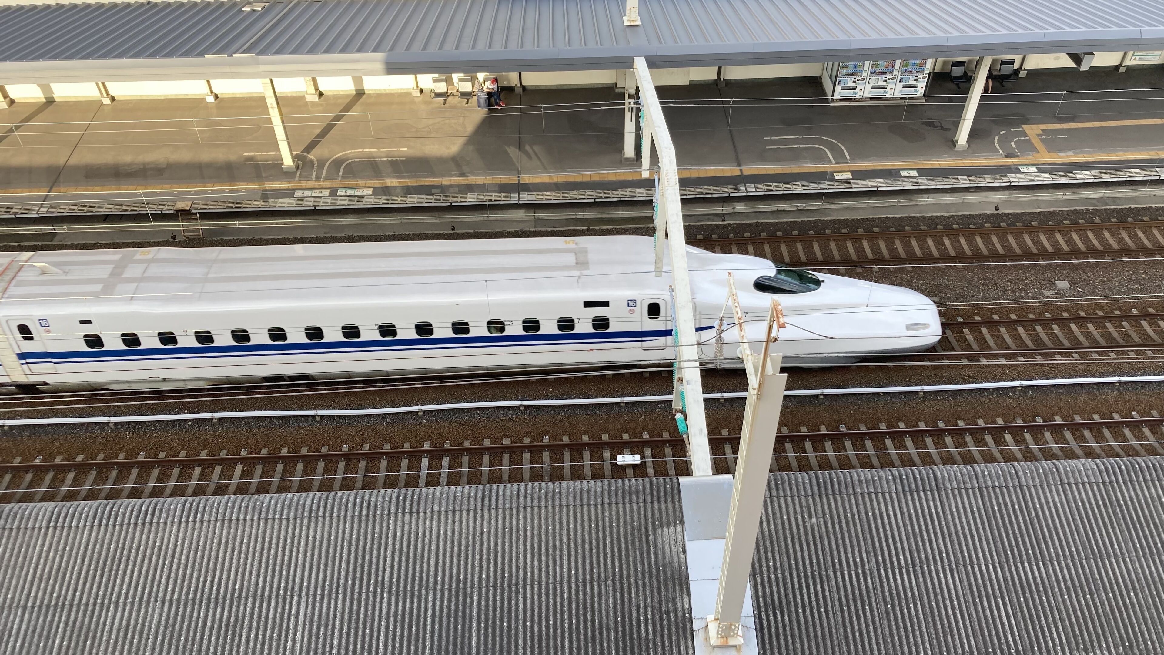 Un andén de estación de tren con un tren blanco sobre las vías.