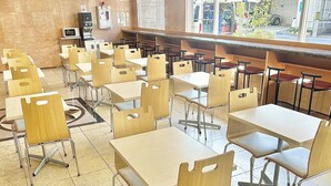 A cafeteria with multiple tables and chairs, a microwave, and a vending machine. - Toyoko Inn Tokuyama Station Shinkansen (Shunan)