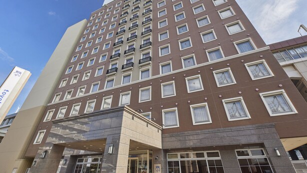 A multi-story hotel with a prominent sign at the top, a modern facade, and a ground entrance with glass doors. - Toyoko Inn Tokuyama Station Shinkansen (Shunan)