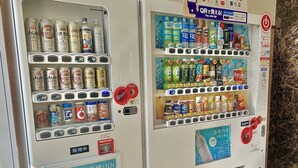 A vending machine with various beverages and snacks, including cans and bottles, and a sign advertising a hotel. - Toyoko Inn Tokuyama Station Shinkansen (Shunan)