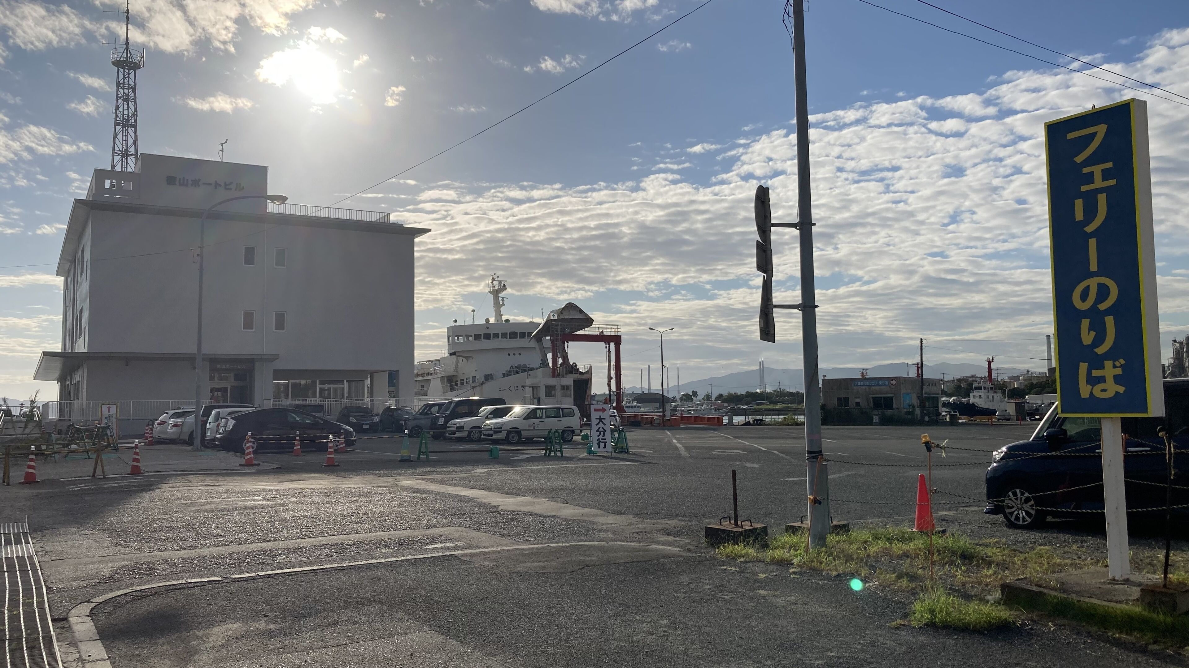 A building with a sign that reads "フェリーのりば" and a parking lot with several cars.
