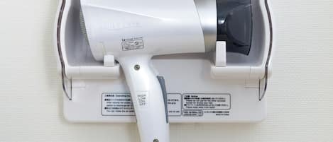 A hair dryer mounted on a wall with a power cord plugged in.