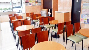 A dining area with multiple tables and chairs, a counter, and a wall with various notices. - Toyoko Inn Miyazaki Chuo-dori (Miyazaki)