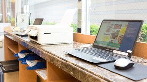 A reception desk with a laptop, a printer, and a computer monitor displaying a website. - Toyoko Inn Miyazaki Chuo-dori (Miyazaki)