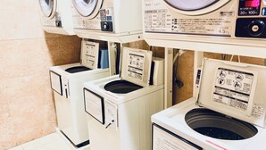 Une laverie équipée de plusieurs machines à laver, chacune dotée d’un panneau de commande et d’un manuel d’utilisation.
