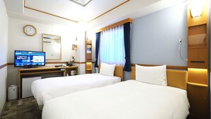 Une chambre d’hôtel avec deux lits, un bureau avec un ordinateur, une horloge et une fenêtre avec des rideaux.