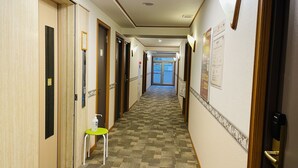 Ein Hotelgang mit mehreren Türen, einem kleinen Hocker und Teppichboden.