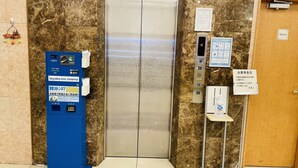 Ein Aufzug mit digitaler Anzeige, einer blauen Fahrkartenmaschine und einem Schild, das einen Privatbereich kennzeichnet.