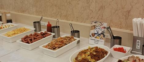 A buffet with various dishes including noodles, hot dogs, and salads.