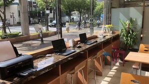 A modern office space with a glass partition, multiple workstations with laptops, a printer, and a few chairs. - Toyoko Inn Takamatsu Hyogomachi (Takamatsu)