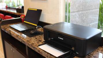 Een receptiebalie met een laptop, een Canon printer en een muis.