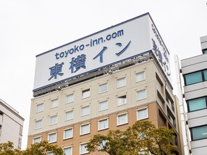 Un edificio con un letrero grande que dice "toyoko-inn.com" en inglés y caracteres japoneses.