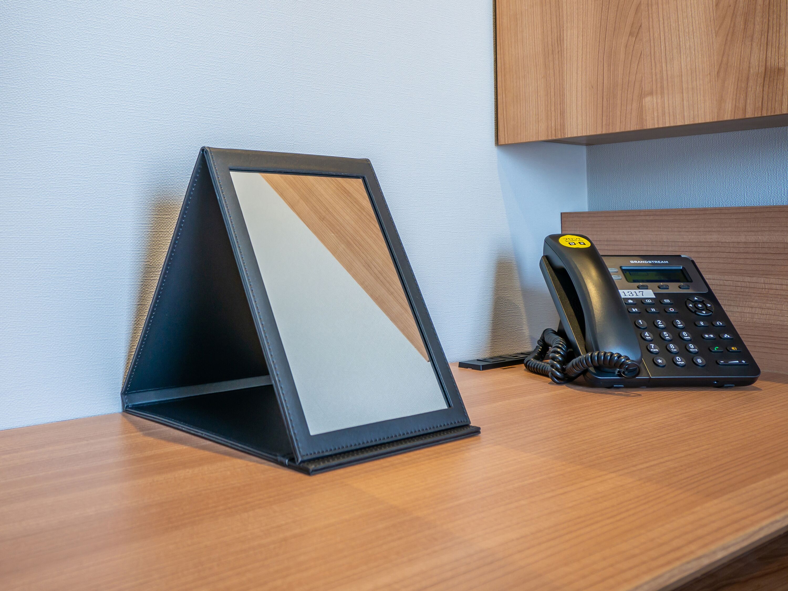 A desk with a black telephone and a framed mirror.
