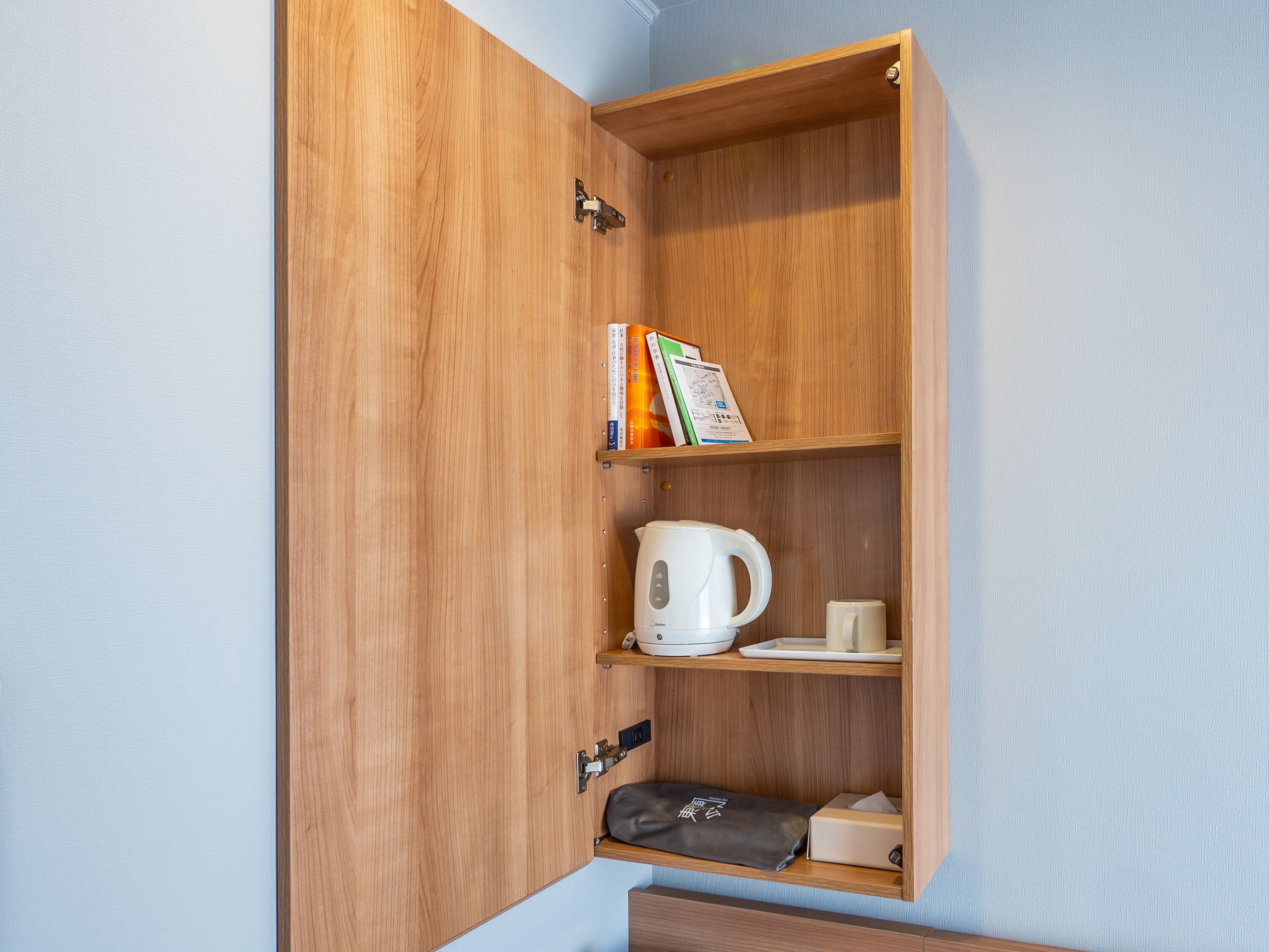 Un meuble en bois contenant une bouilloire blanche, une tasse et un petit sac.