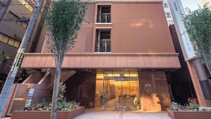 Ein modernes Hotel mit auffälligem Schild, Glastür und einer klaren Fassade.