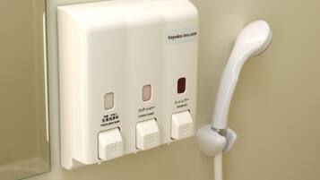 A wall-mounted hotel phone and a shampoo station with buttons for face and body wash, and conditioner.