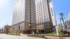 A multi-story hotel with a modern design, featuring a prominent entrance and a visible parking sign.