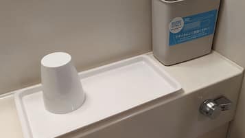 A restroom with a white urinal, a trash bin, and a soap dispenser.