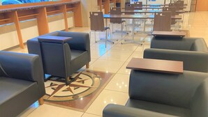 A modern hotel lobby with leather seating, a central dining area, and a star-patterned floor design.