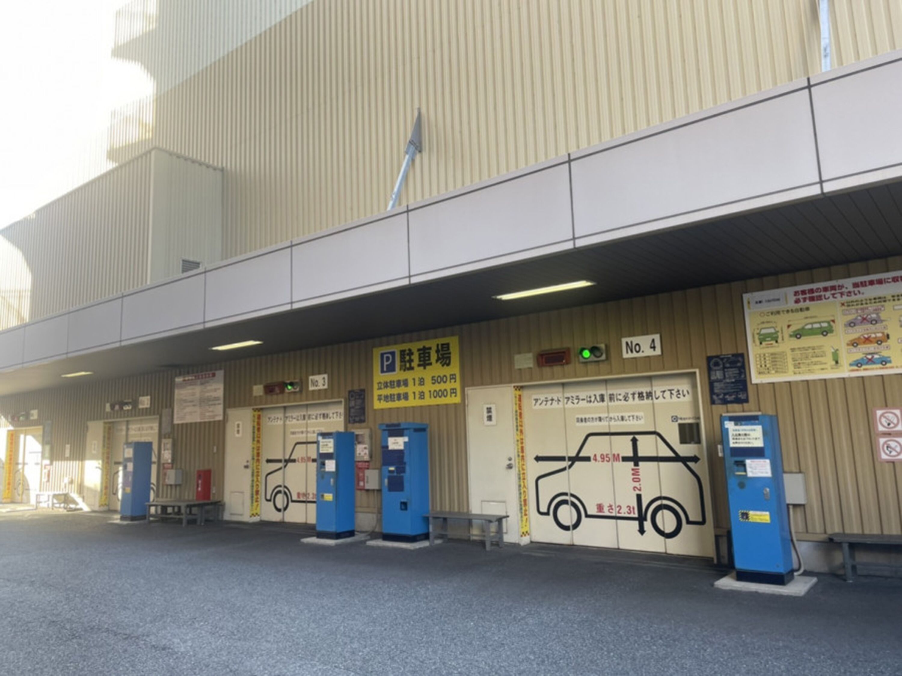A parking garage with multiple levels, marked parking spaces, and a sign indicating a parking fee of 500 yen for 1 hour and 1000 yen for 1 day.