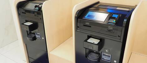 Two self-service kiosks in a modern, clean room with a blue carpet.
