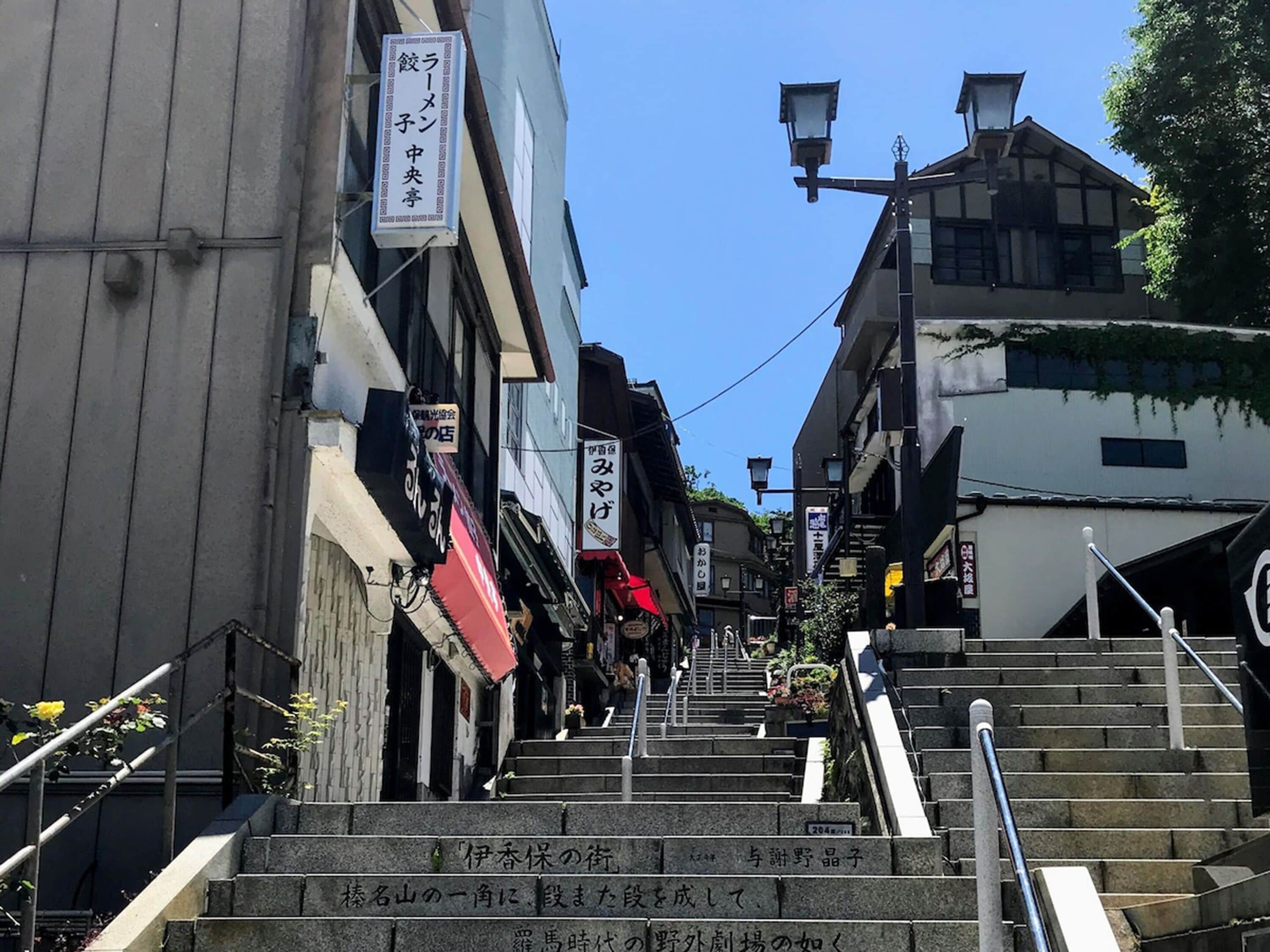 A staircase leading up to a building with multiple signs in Japanese.