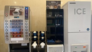 Una máquina de café Nescafé con diversas opciones de bebidas, un dispensador de agua y un dispensador de hielo.