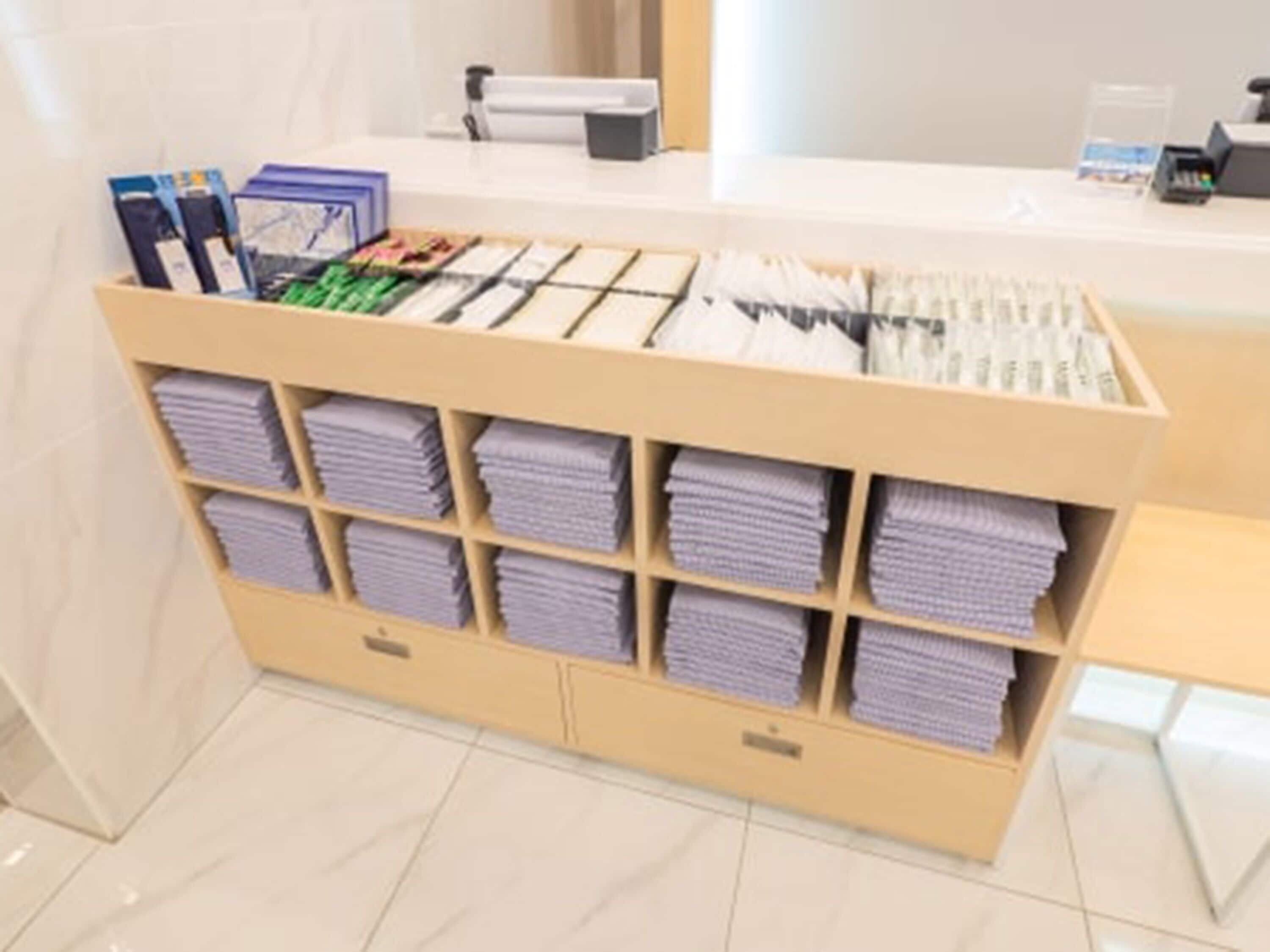 A reception desk with a counter, a printer, and a storage unit with folded towels.