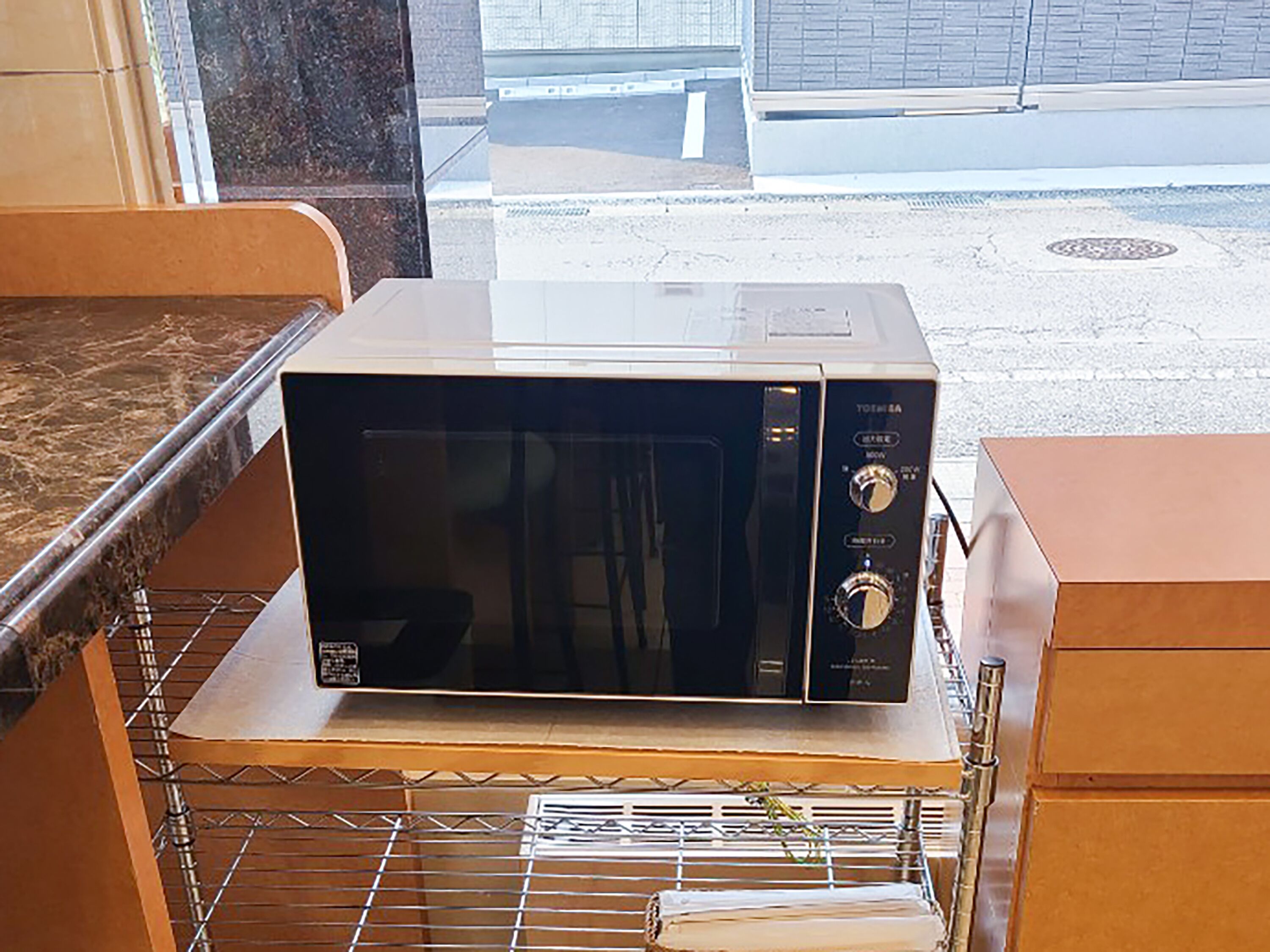En mikrovågsugn placerad på ett metallställ inuti ett rum med en bänkskiva av marmor.