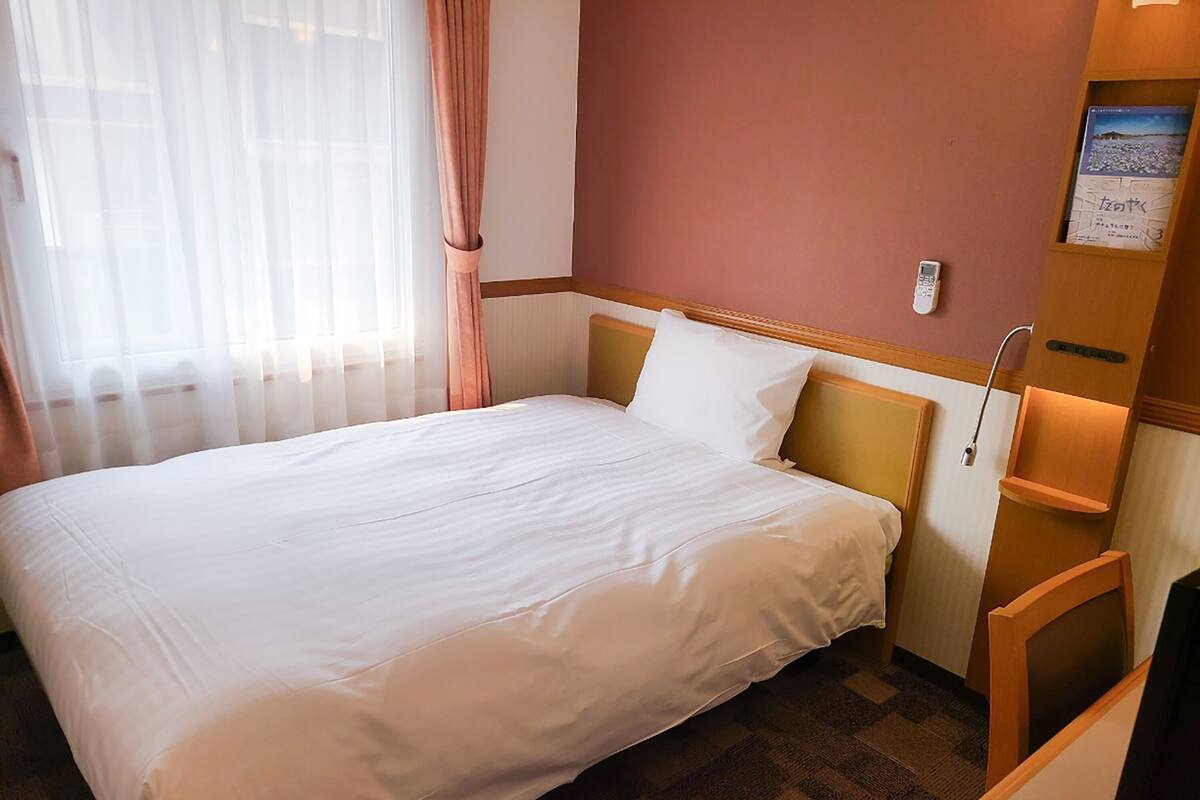 Un lit bien fait, avec du linge de lit blanc, dans une chambre d'hôtel.