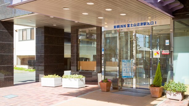 A modern building entrance with a covered walkway, glass doors, and potted plants. - Toyoko Inn Fujisan Numazu Station Kita 1 (Numazu)