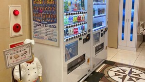 A vending machine with a poster advertising a soccer team, a fire extinguisher, and a breakfast service sign. - Toyoko Inn Fujisan Numazu Station Kita 1 (Numazu)
