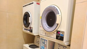 A laundry facility with three stacked washing machines, each with a control panel and safety instructions. - Toyoko Inn Fujisan Numazu Station Kita 1 (Numazu)