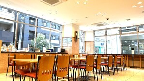 A spacious indoor dining area with multiple tables and chairs, large windows offering views of the city, and a modern interior design. - Toyoko Inn Nagoya Owari Ichinomiya Ekimae (Ichinomiya)