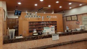 A reception area with a 'FRONT' sign, a digital screen, and a counter with various items.